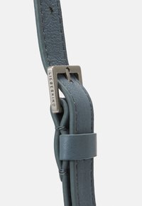 Cinturino in pelle di blu tenue, con una fibbia in metallo argentato con marchio inciso. Superficie liscia con minima texture e linee pulite.