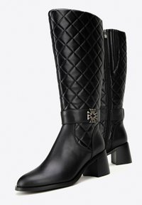 Czarne wysokie do kolan botki z pikowanym wzorem, gładka skóra, okrągłe palce i niski klinowy obcas. Posiadają srebrną ozdobną klamrę.