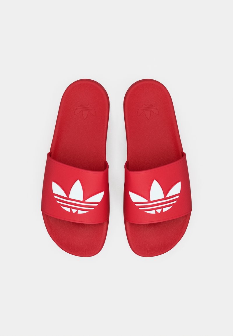 Røde gummisandaler med bred rem og et hvidt trekløverlogo med tre horisontale striber. Glat tekstur og afrundet form.