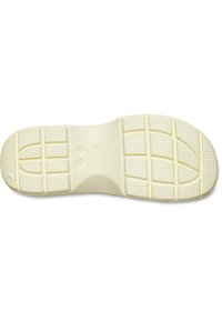 Podeszwa Crocs, w kolorze kości słoniowej, wykonana z elastycznego materiału, z teksturowanym bieżnikiem zapewniającym przyczepność, z zaokrąglonymi wzorami i wytłoczonymi detalami logo.