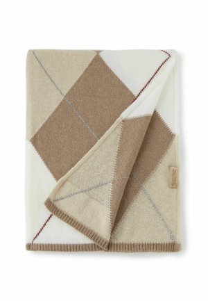 Couverture en laine pliée avec un motif losanges beige, marron et blanc et une petite étiquette en tissu sur le bord.