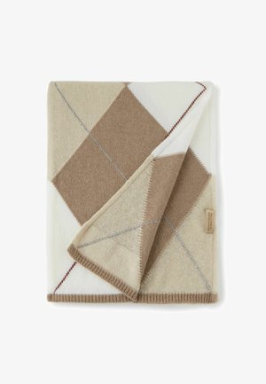 Couverture en laine pliée avec un motif losanges beige, marron et blanc et une petite étiquette en tissu sur le bord.