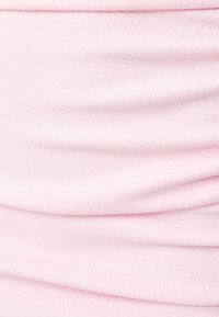 Vaaleanpunainen kangas, jossa on tekstuuri pinta, pehmeillä laskoksilla ja sileällä ulkonäöllä, ideaalinen vaatteisiin tai asusteisiin.