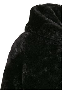 Svart fuskpälsjacka med huva, som har en mjuk, strukturerad yta och en avslappnad design. Tyget ser fluffigt och varmt ut.