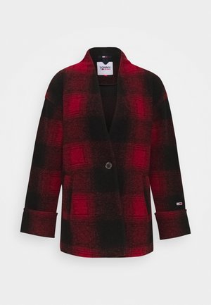 Červený a černý kostkovaný vlněný kabát s klopeným límcem, zapínáním na jeden knoflík a širokými rukávy. Obsahuje logo na manžetě.
