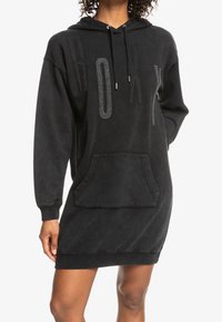Robe hoodie noire en tissu doux, avec une poche avant, des poignets côtelés et un lettrage 'ROXY' audacieux dans un motif texturé.