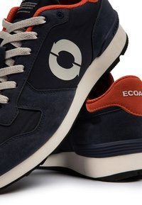 Baskets bleu marine avec semelles blanches, lacets gris clair, doublure intérieure orange, logo circulaire sur le côté et marquage ECOALF au talon.