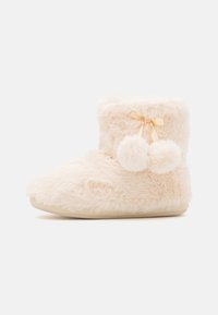 Furry light pink ankle boot with pom-poms and ribbon detail, featuring a soft texture and flat sole. Simple design for indoor wear.