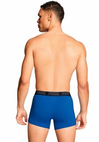 Boxer blu realizzati in tessuto elasticizzato con design a tinta unita e cintura elastica nera con il marchio "PUMA" in lettere bianche.