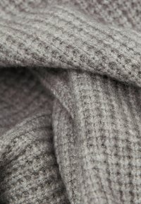 Teksturalny, miękki szary materiał o prążkowanym wzorze, charakteryzujący się puszystą powierzchnią i warstwowym wyglądem, idealny do zapewnienia ciepła i komfortu.