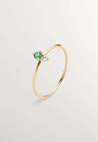 Anillo de oro con una banda lisa y dos piedras preciosas: una piedra verde y un diamante claro, diseñado de forma minimalista con engastes de garra.