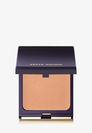 Compact poeder met een paarse behuizing en gouden accenten. De textuur van het poeder is lichtbruin. Klapdeksel sluiting.