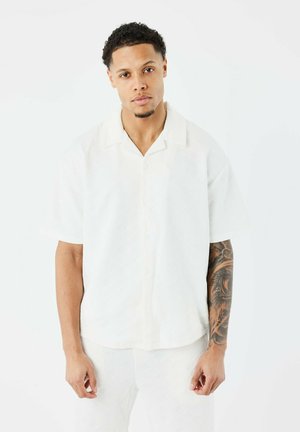 White short-sleeve shirt with a textured fabric, button front, and a relaxed collar. Features an overall light and clean appearance.