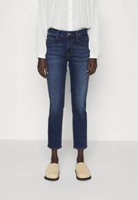 Tmavě modré džínové kalhoty se rovnými nohavicemi, středním pasem a klasickým designem s pěti kapsami. Obsahují jemný efekt zesvětlení a šité švy.