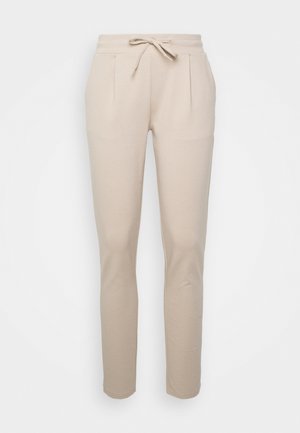 Pantalons de jogging beige clair en tissu doux, dotés d'une taille élastique avec cordon de serrage, de poches latérales et d'une coupe fuselée.