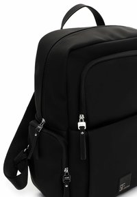 Juoda kuprinė iš lygaus audinio, su stačiakampio formos dizainu, keliais užtrauktukais uždaramais skyreliais ir sidabrinėmis detalėmis.