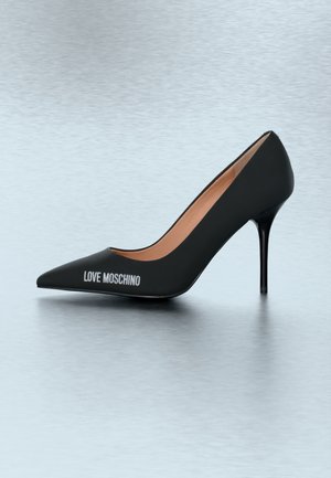 Black pointed-toe high heel pump with "LOVE MOSCHINO" text on the side and tan interior, displayed on a light gray surface.