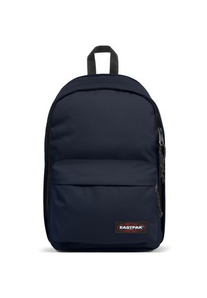 Mochila de color azul marino hecha de un tejido duradero, con un bolsillo frontal con cremallera y un asa superior. Textura suave, forma rectangular, parche de marca.