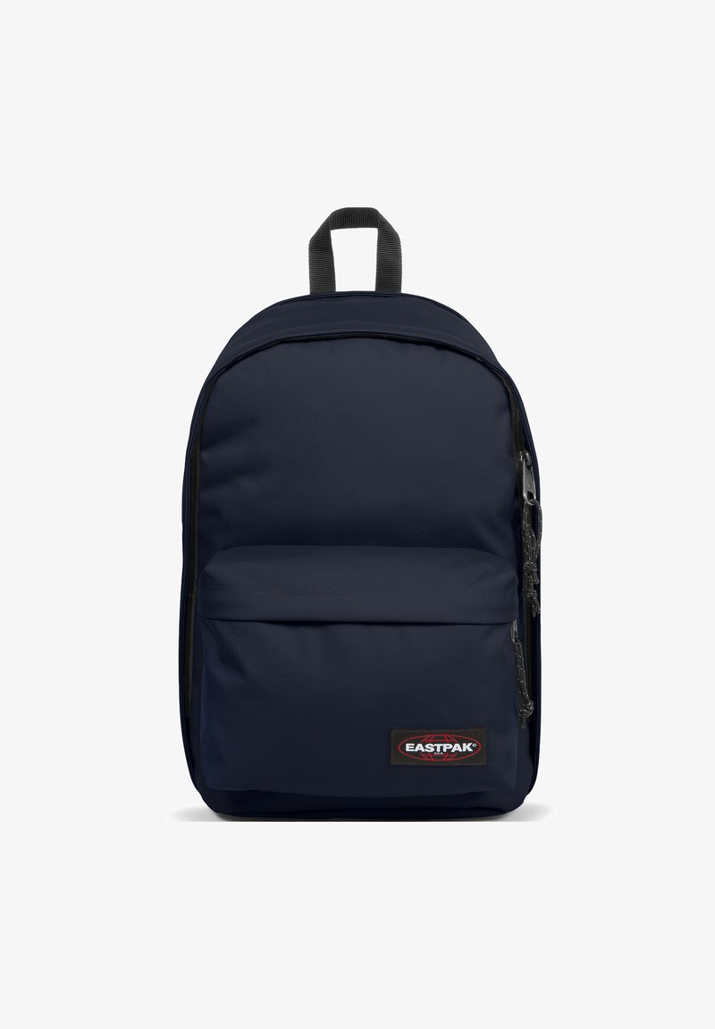 Mochila de color azul marino hecha de un tejido duradero, con un bolsillo frontal con cremallera y un asa superior. Textura suave, forma rectangular, parche de marca.