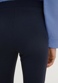 Leggings blu navy realizzati in un tessuto morbido e testurizzato, con vita media, abbinati a una maglietta azzurro chiaro che presenta un design senza cuciture.