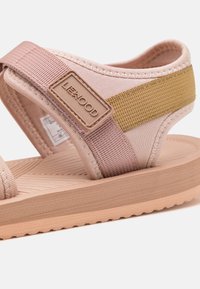 Rosa und beige Sandalen mit geflochtenen Riemen, strukturiertem Gummisohle und einem Markenakzent; leicht und für Komfort ausgelegt.