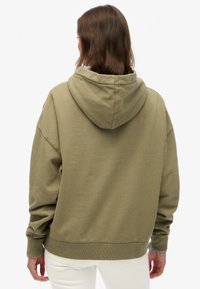 Felpa con cappuccio verde oliva, dal taglio rilassato, con polsini e orlo a costine. Tessuto testurizzato con design del cappuccio senza cuciture.
