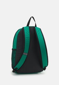 Sac à dos avec un corps noir et des accents verts, une texture de tissu lisse, des bretelles rembourrées et une poche en mesh sur le côté pour le rangement.