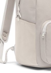 Világosszürke hátizsák, texturált anyagból készült, cipzáras zsebekkel és párnázott vállpánttal, hálós részletekkel a kényelmes viselet érdekében.