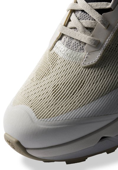 Baskets de sport beiges avec un dessus en tricot texturé, des accents synthétiques lisses et un col rembourré pour le confort. Semelle légère.