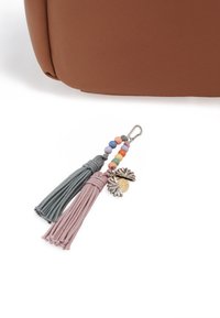 Bruine neplederen tas met een sleutelhanger die twee stoffen franjes in teal en pastelroze, kleurrijke kralen en een metalen charm bevat.