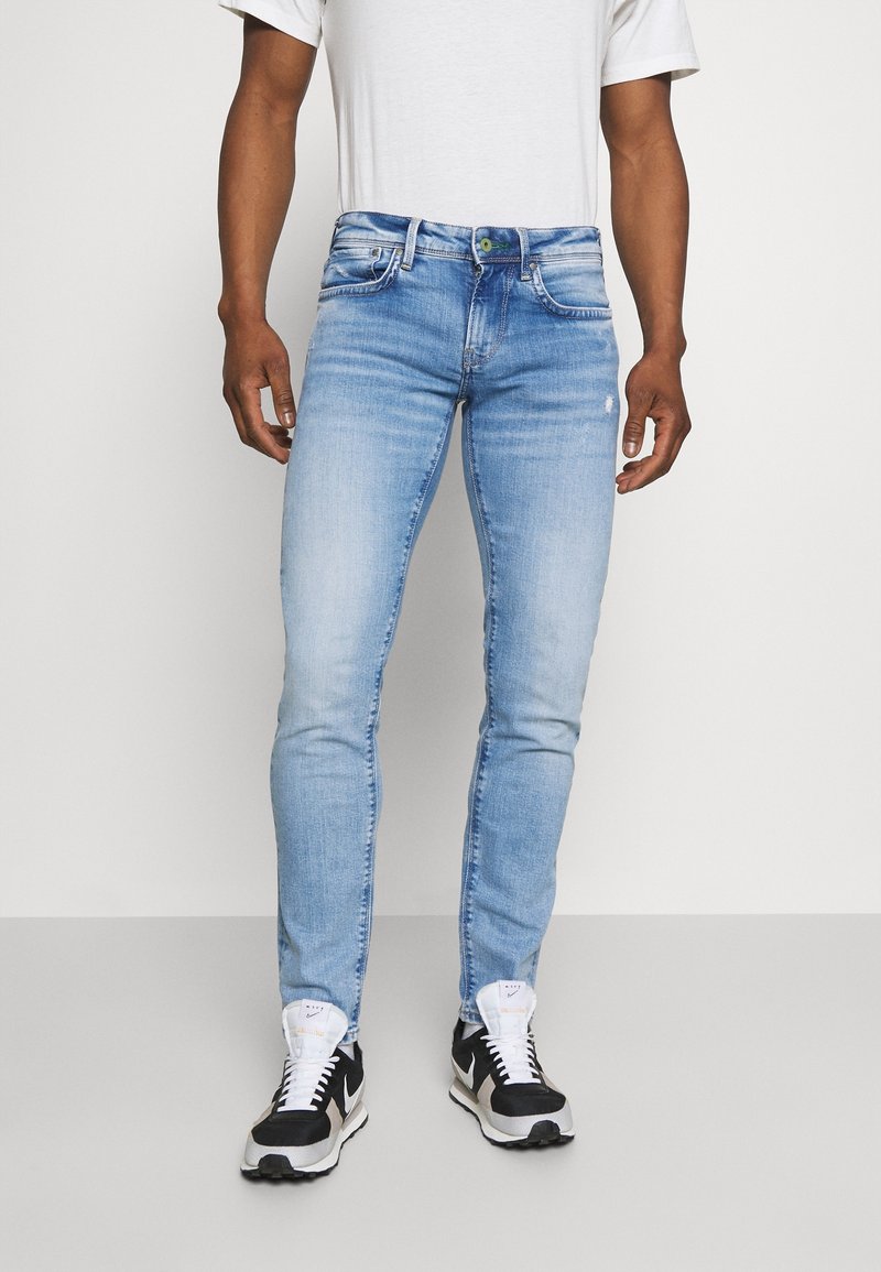 Ljusblå jeans i slim fit med fem fickor, lätt tvättade och med en grön knappdetalj vid midjan.