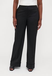 Black trousers with a tailored fit, wide legs, and a flat waistband. Features a button closure and turned-up cuffs. Smooth texture.
