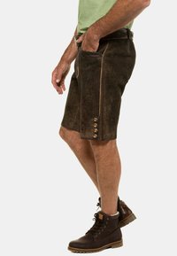 Pantalones cortos de cuero marrón con un acabado texturizado, que cuentan con un bolsillo lateral, costuras decorativas y botones de metal en el dobladillo.