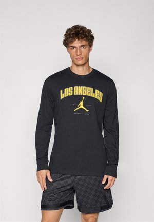 Sort langærmet skjorte med gul "LOS ANGELES" tryk og Jumpman-logo; parret med sorte mønstrede shorts. 100% bomuldsmateriale, afslappet pasform.