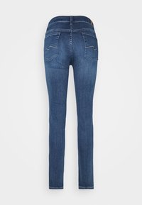 Jeans de mezclilla azul con un diseño ajustado, pierna recta y dos bolsillos traseros con detalles de costura en contraste. Pasadores para cinturón en la cintura.