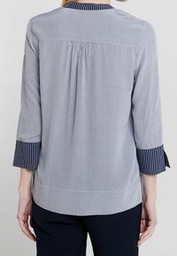 Raidallinen paita rentoa estetiikkaa, jossa on laskostettu takaosa, kolmen neljänneksen hihat raidallisilla hihoilla ja pehmeä, kevyt kangas.