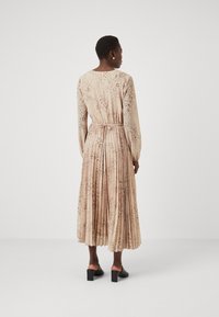 Μακρυμάνικη, πλισέ φόρεμα σε ανοιχτό μπεζ με διακριτικό σχέδιο ζώου, που διαθέτει ελαστική μέση και μαλακή, ρέουσα υφή.