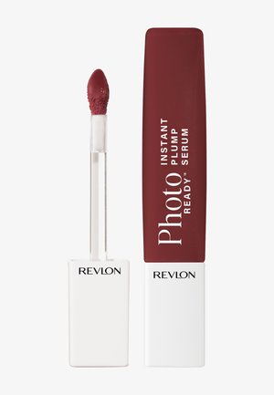 Siero labbra con punta applicatore di colore rosso intenso e tappo rettangolare abbinato etichettato "Photo Ready Instant Plump Serum" di Revlon.