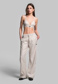 Beige Bralette mit vertikalen Streifen und verstellbaren Trägern, kombiniert mit passenden weit geschnittenen Hosen mit Kordelzug und Seitentaschen.