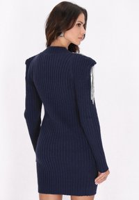 Robe en tricot côtelé navy à manches longues, ornée d'accents en franges argentées sur les épaules et d'une silhouette cintrée.