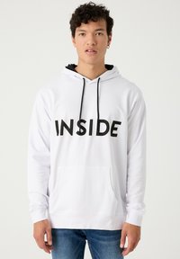 Sudadera blanca con capucha, que presenta el texto negro "INSIDE" en la parte frontal, cordones negros y un bolsillo tipo canguro en la parte delantera.