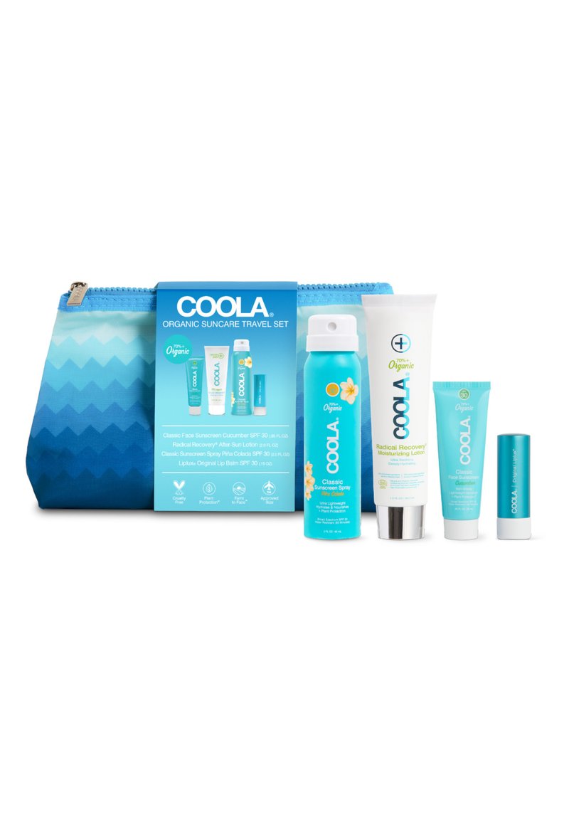 Reiseset mit einer blauen Gradient-Tasche mit Zickzackmuster, die fünf Hautpflegeprodukte in Tuben und einer Sprühdose enthält.