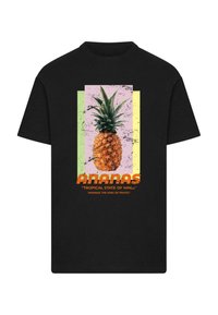 Fekete, rövid ujjú póló ananász grafikával, színes háttér négyzetekkel, és felirattal: "ANANÁS" és "TROPICAL STATE OF MIND."