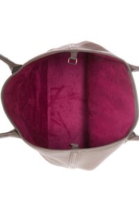 Handväska av kornigt läder med ett livfullt fuchsialila foder, två huvudfack och en mittendelare med clips.