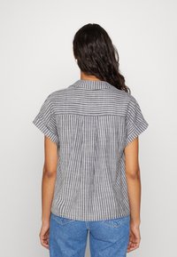 Gestreepte shirt met korte mouwen in grijs en wit, voorzien van een kraag en plooien aan de achterkant. Gemaakt van lichtgewicht, geweven stof.