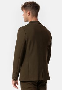 Blazer verde oliva con una vestibilità su misura. Presenta un colletto con rever, una fessura posteriore singola e tre bottoni sui polsini delle maniche.