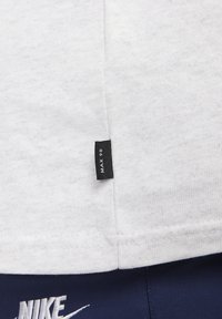 Witte katoenen t-shirt met een klein zwart label met de tekst "MAX 90" op de ondernaad, met een gladde, textuurachtige stofafwerking.