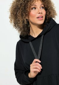 Schwarzer Hoodie mit texturiertem Kordelzug, langen Ärmeln und einer entspannten Passform. Der Stoff wirkt weich, mit einem gerafften unteren Saum.