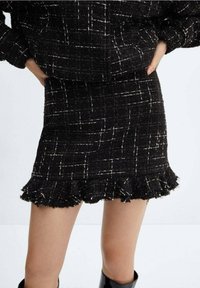 Zwarte tweed mini-jurk met wit geruite patroon, franjes aan de onderkant en een gestructureerde stof, gecombineerd met een bijpassende jas.