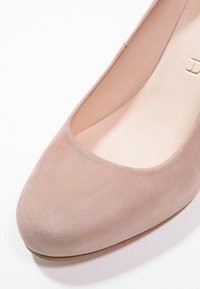 Beige semišové lodičky s kulatou špičkou, hladkým vnitřním podšíváním a decentním podpatkem. Plochá podrážka a minimální detaily dodávají klasický vzhled.